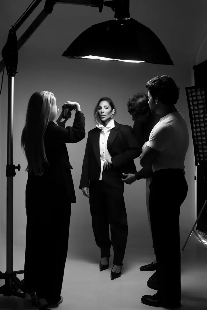 Bastidor de sessão do CMF Studio: modelo dirigida sob softbox, com a equipe ajustando luz e styling.