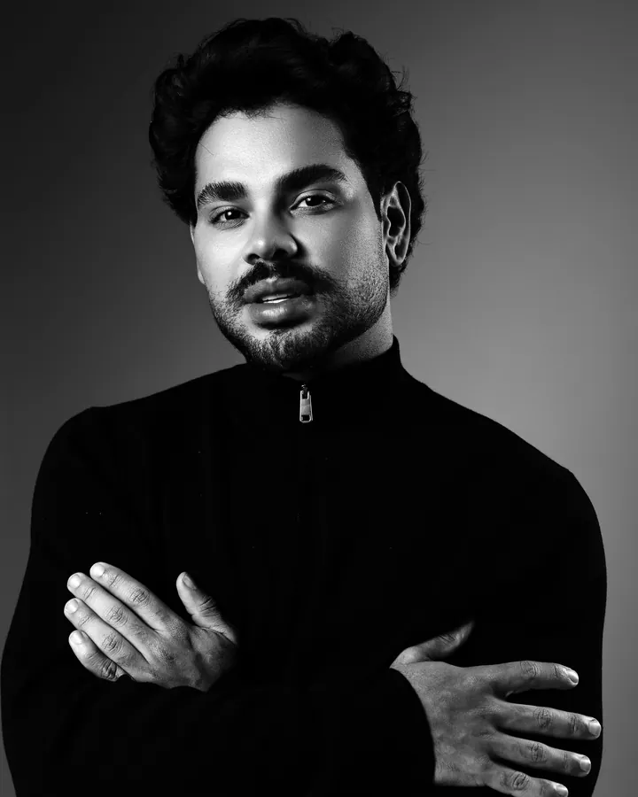 Vitor Ferreira de braços cruzados, olhando para a câmera, retrato de estúdio em preto e branco.